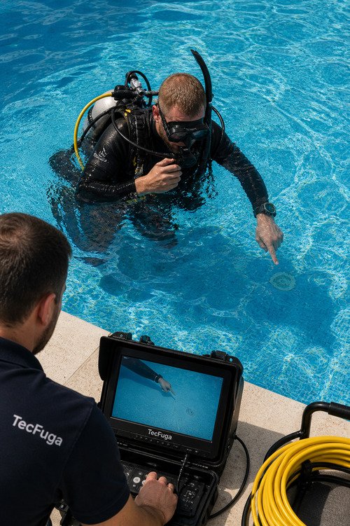 Técnico a realizar deteção de fugas em piscina com vídeo inspeção enquanto mergulhador identifica fissura no fundo