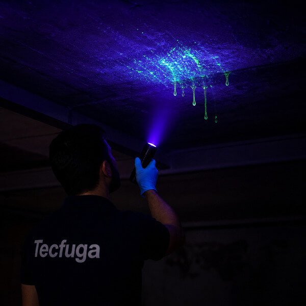 Deteção de infiltração no teto com luz ultravioleta e corante traçador químico a evidenciar fuga de água