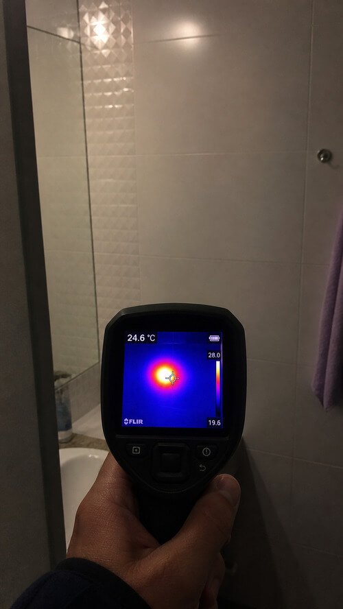 Câmara termográfica a identificar fuga de água oculta em tubulação de água quente atrás de azulejo em casa de banho