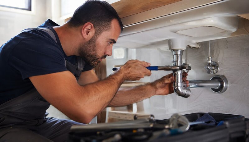 Canalizador profissional a realizar reparação e manutenção de canalização numa instalação hidráulica residencial