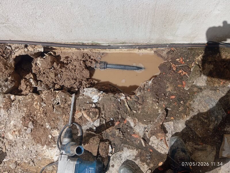 Tubagem de abastecimento de água exposta após a localização precisa da fuga junto ao muro exterior de uma moradia em Sintra.