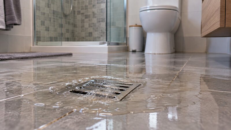 Água a regressar por um ralo de pavimento devido a uma possível obstrução na rede de drenagem.