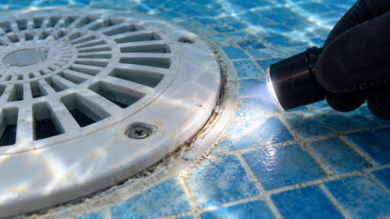 Pormenor da união entre o ralo de fundo e o revestimento da piscina durante uma verificação da vedação.